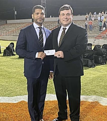 Derrick Mills (left) is shown presenting checks to Fayette Principal Dr. Jeremy Madden during graduation.